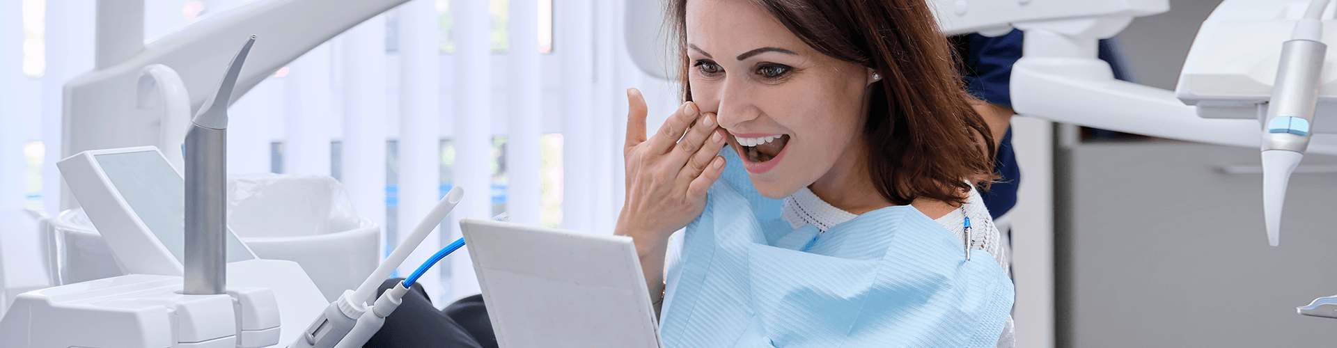 dental patient admiring her smile in a handheld mirror