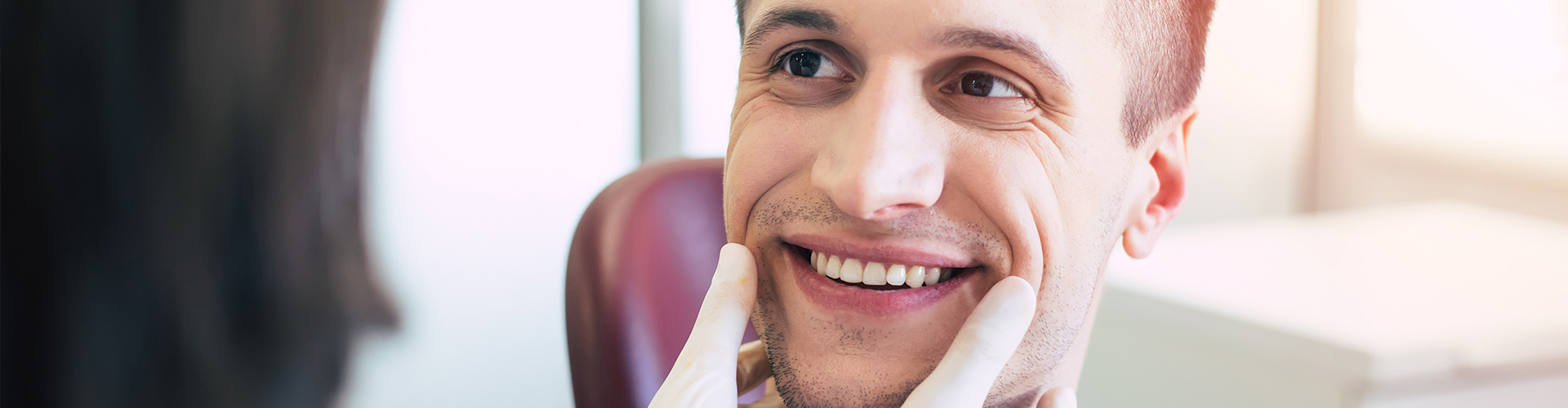 Gloved hands framing man's smile.