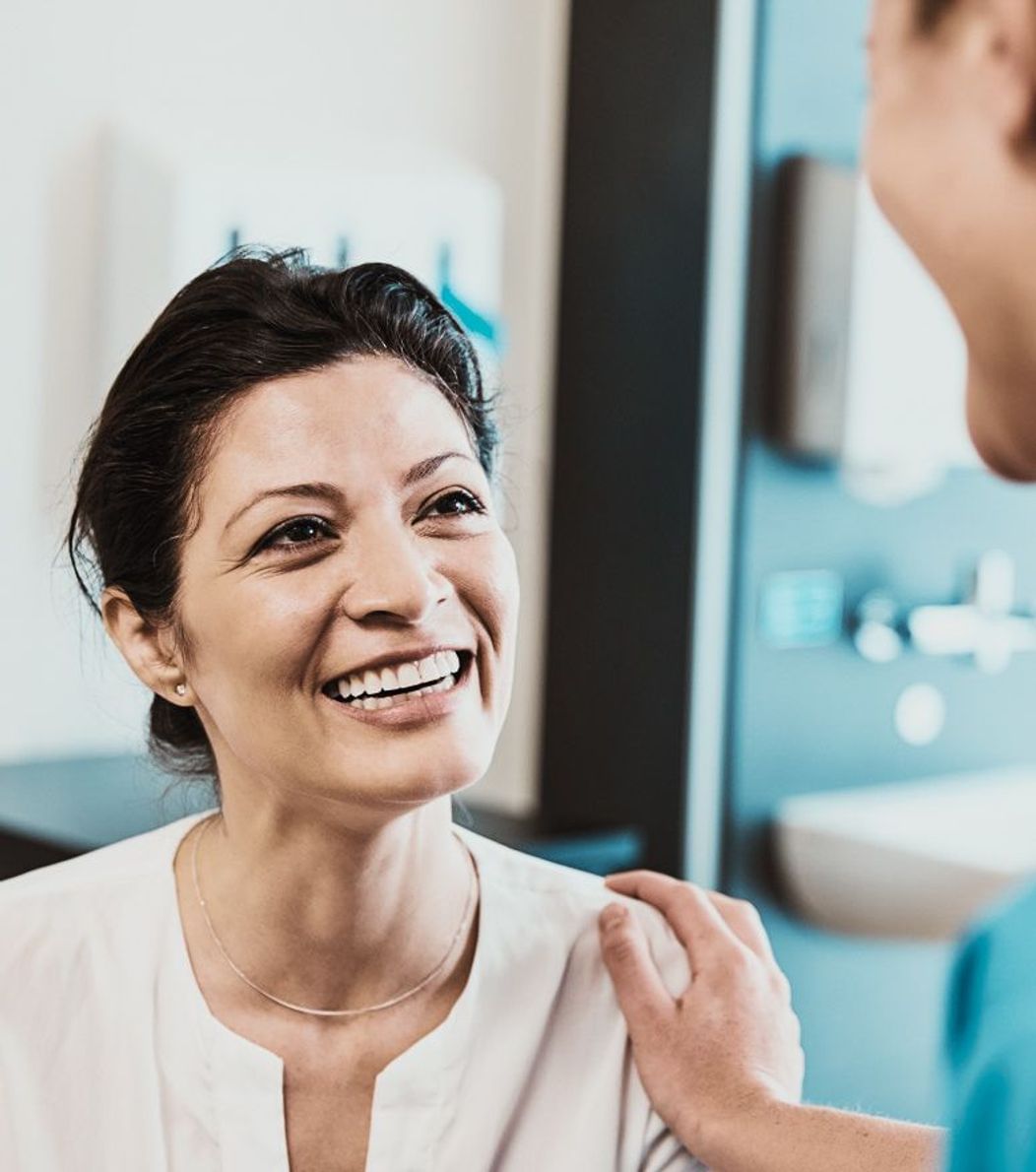 An image of a dentist reassuring a smiling female patient