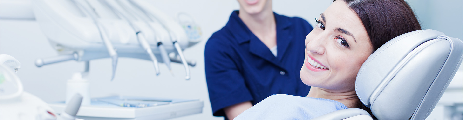 A patient seated in the dentist chair with the dentist standing beside them, smiling at the camera.