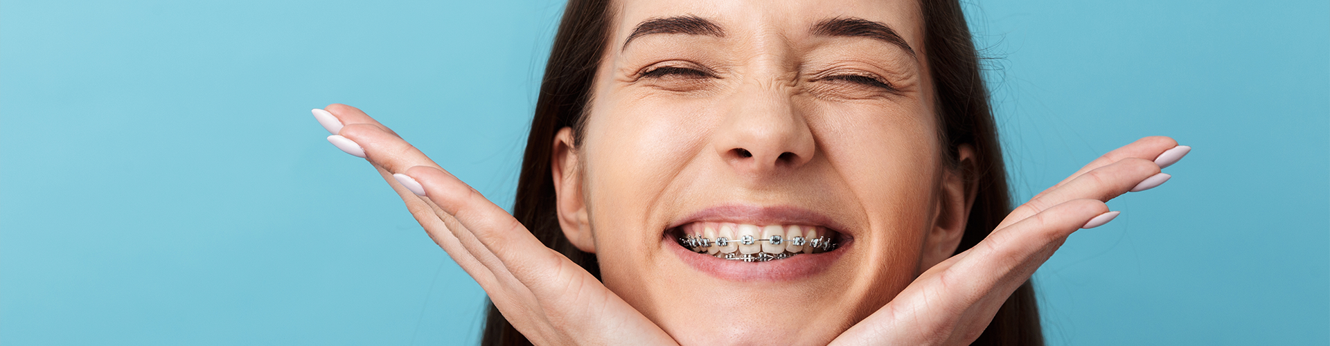 Smiling woman holding her cheeks in her hands.