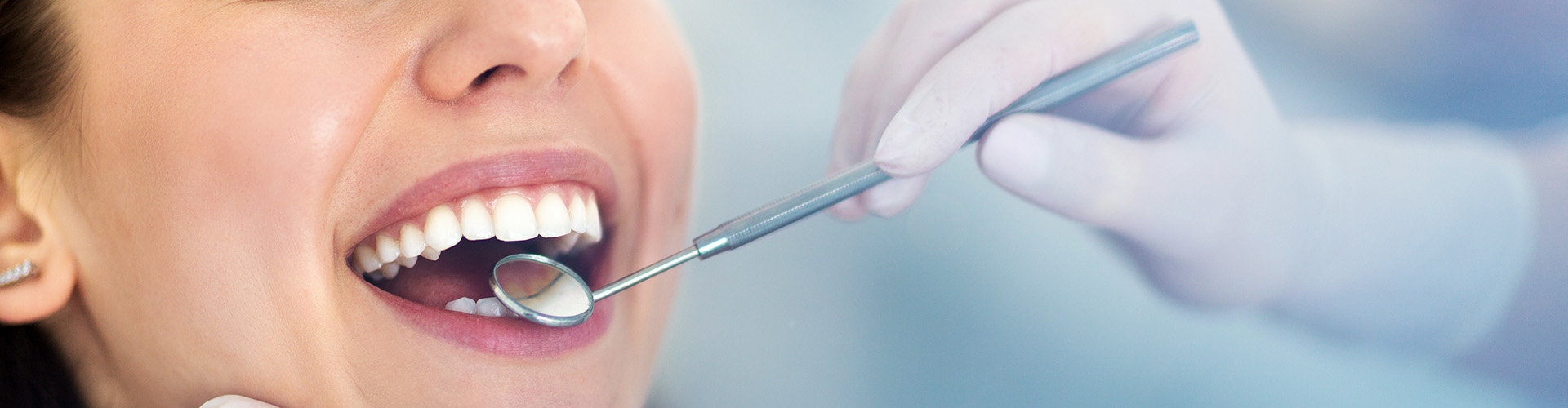 dentist holding a dental mirror in a woman's mouth