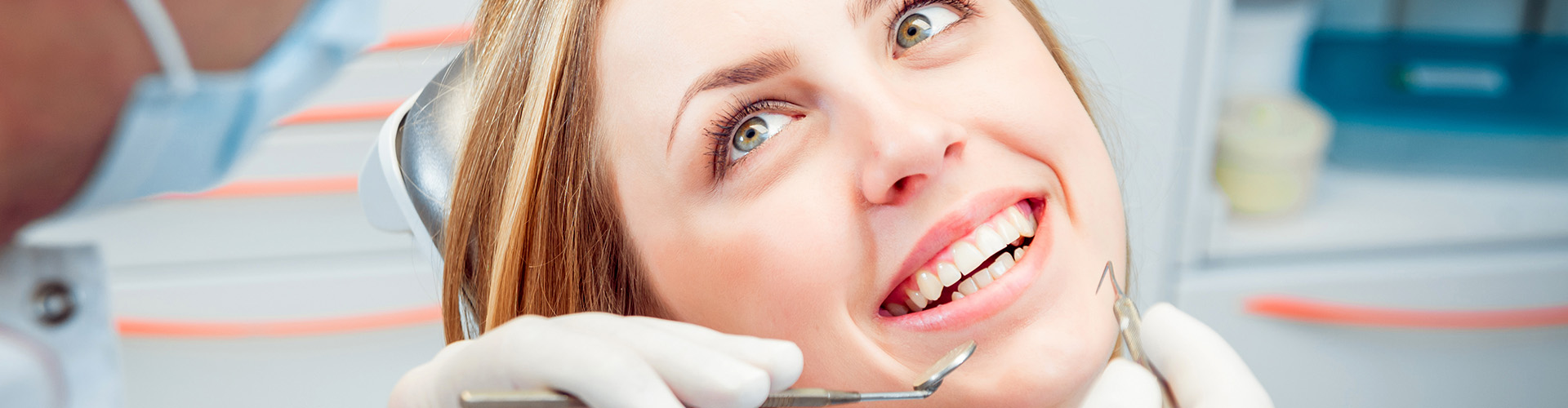 A girl smiling while being examined by a dentist.