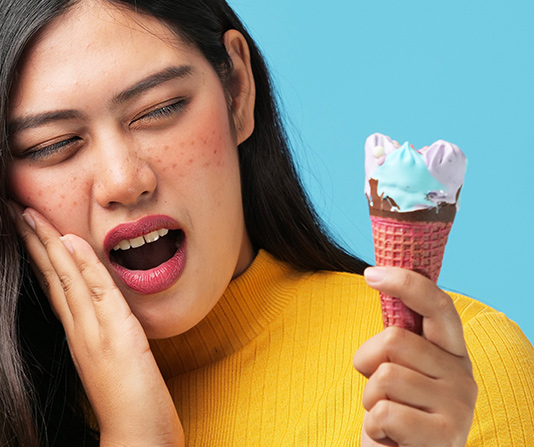 Woman eating ice cream and suffering discomfort and oral sensitivity
