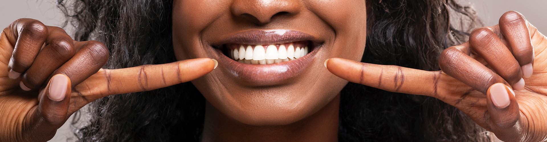 Woman pointing at her smile with both hands.