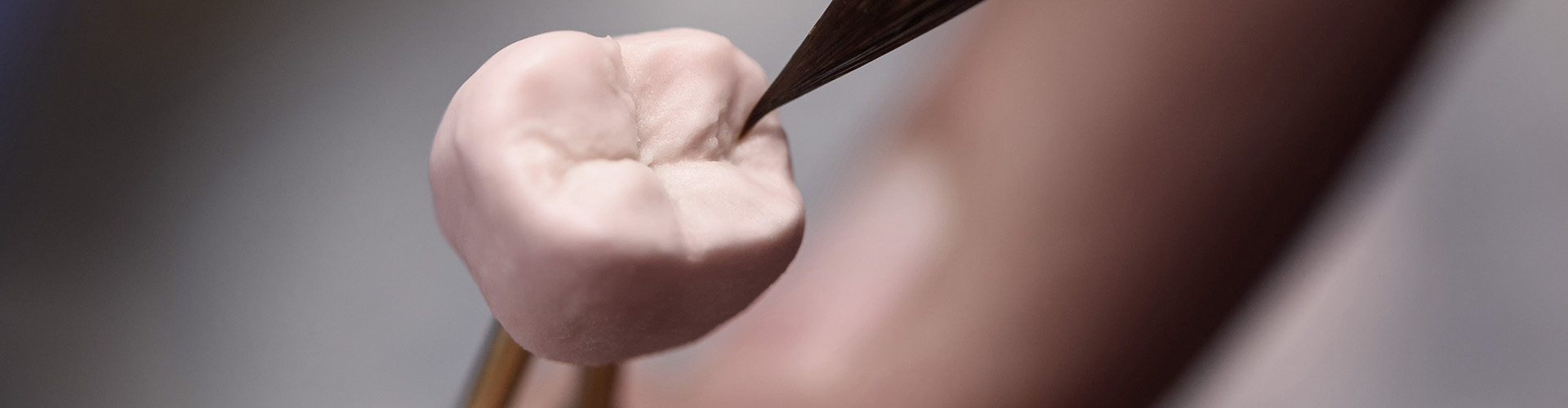 Tweezers holding a crown while it is shaped.