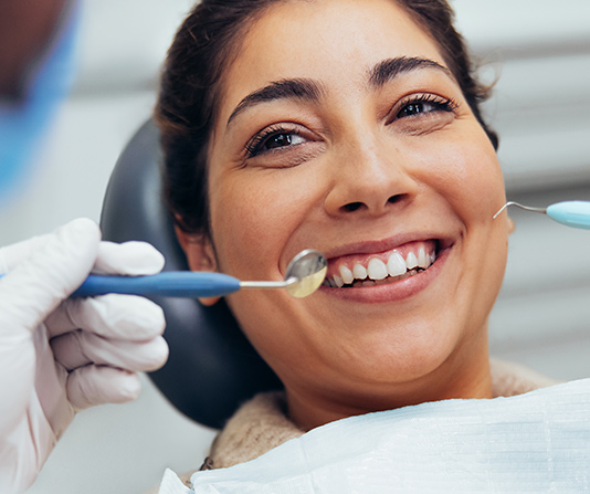 Smiling woman in dental chair having oral examination.