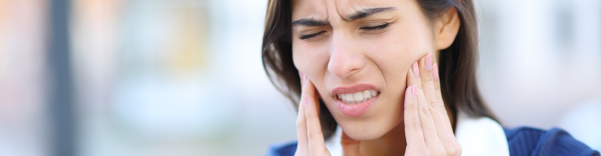 A woman holding her cheeks with her hands, showing discomfort.